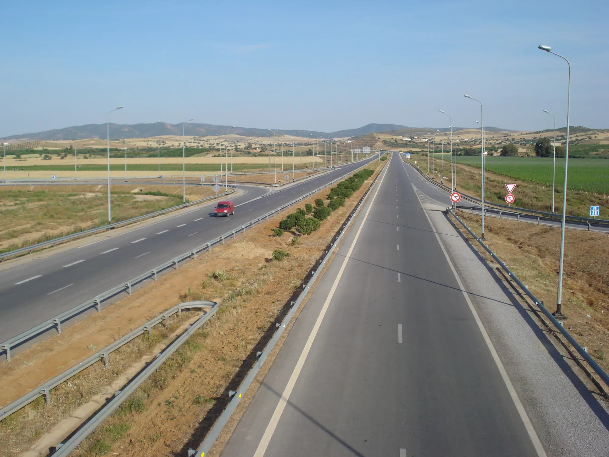 A car on the open motorway west of Tunis, with wheat fields and hills ahead